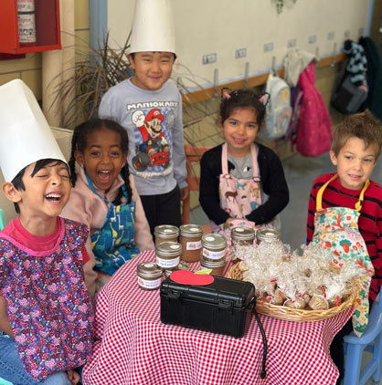 Montessori students with chef hats on around a table with food